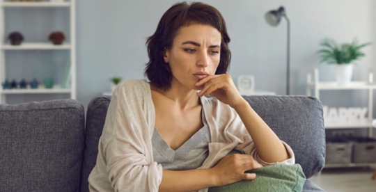 woman with a worried look on her face sitting on the couch